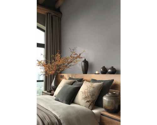 Modernes Schlafzimmer mit grauer Vliestapete, Holzkopfteil, Kissen mit Baummotiv und dekorativen dunklen Vasen.
