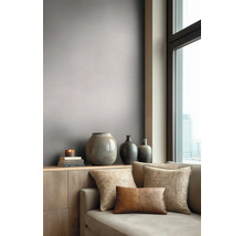 Modernes Wohnzimmer mit graubrauner Tapete, Sofa mit Dekokissen und Vasen auf einem Sideboard neben einem großen Fenster.