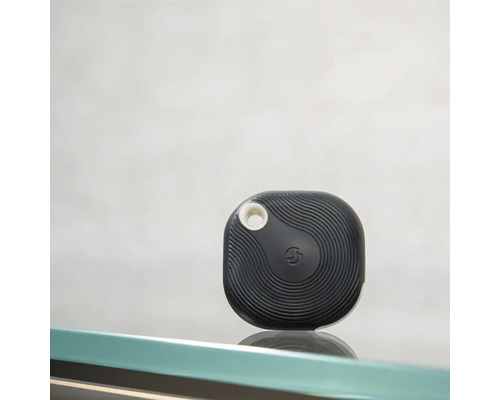 Schwarzer Bluetooth-Tracker mit Wellenmuster und runder Öffnung zur Befestigung.
