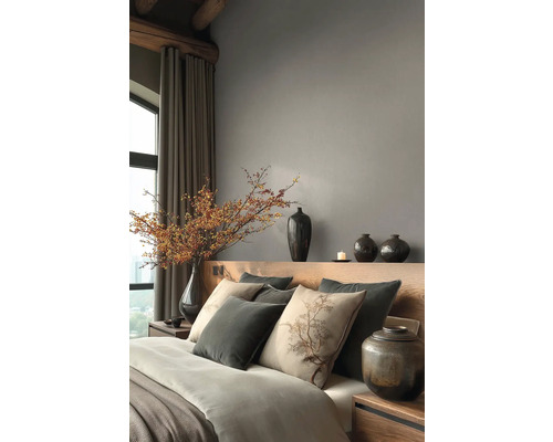 Modernes Schlafzimmer mit Kopfteil aus Holz, grauen Wänden, Zierkissen, Keramikvasen und einem großen Zweig mit Beeren in einer Vase.