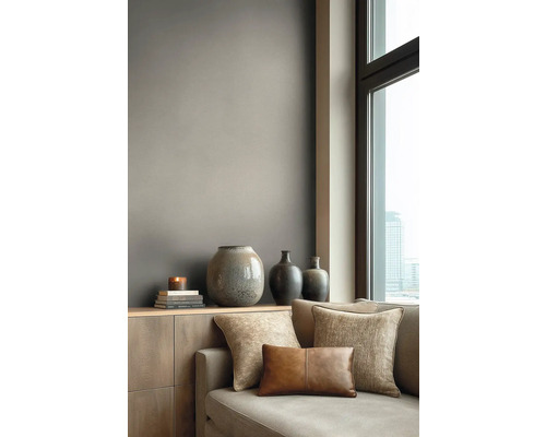 Modern gestalteter Wohnraum mit einer Wand in mattem Taupe hinter einem Sideboard aus Holz mit Vasen und einem Sofa neben einem Fenster.
