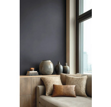 Modernes Wohnzimmer mit dunkler Wandfarbe, Holzkommode, Keramikvasen und Sofa mit strukturierten Kissen vor einem Fenster mit Stadtblick.