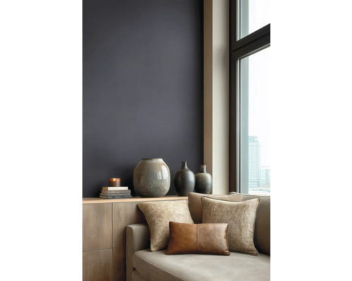 Modernes Wohnzimmer mit dunkler Wandfarbe, Holzkommode, Keramikvasen und Sofa mit strukturierten Kissen vor einem Fenster mit Stadtblick.