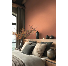 Schlafzimmer mit Bett, Kissen, Vasen und Dekoration in warmen Farbtönen