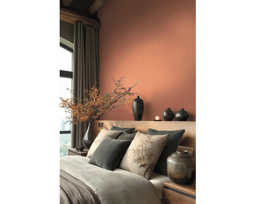 Schlafzimmer mit Bett, Kissen, Vasen und Dekoration in warmen Farbtönen