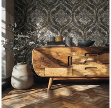 Wohnzimmerszene mit Vliestapete mit Ornamenten, einem Sideboard aus Holz und Parkettboden.