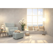 Helles Wohnzimmer mit Sessel, Fußhocker und großem Fenster