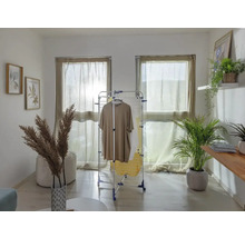 Wohnraum mit Wäscheständer, Kleidung, Fenstern mit Vorhängen und Dekorationen.