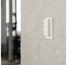 Smarter Wandschalter aus Kunststoff mit vier Tasten zur Lichtsteuerung an einer strukturierten Wand.