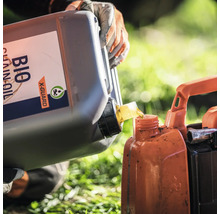Eine Person gießt Bio-Kettenöl in einen Behälter.