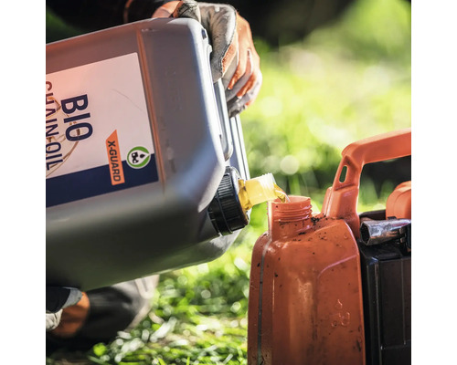 Eine Person gießt Bio-Kettenöl in einen Behälter.