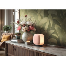 Moderne, quaderförmige Tischleuchte mit sanftem Licht auf einem Sideboard mit Marmorplatte, Blumenstrauß in Vase und Tapete mit Blattmuster.