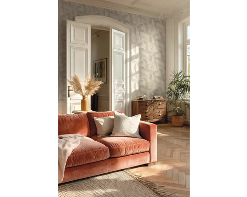 Helles Wohnzimmer mit Vliestapete mit Blattmuster, Fischgrätparkett, orangefarbenem Samtsofa und einer Kommode aus Holz.
