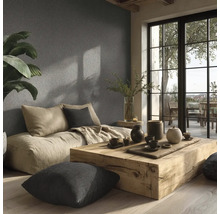 Helles Wohnzimmer mit Sitzkissen, Holztisch und Dekoration vor einer strukturierten Wand
