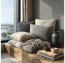 Dekorative Kissen und eine Decke auf einer Holzbank neben einem Fenster mit Ausblick