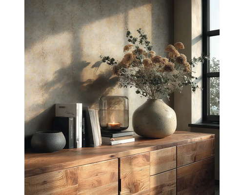 Holz-Sideboard mit Stein-Vase, Trockenblumen, Glas-Laterne mit Kerze und Büchern vor einer strukturierten Tapete in warmem Sonnenlicht.