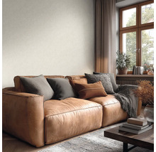 Hellbraunes Ledersofa in einem hellen Wohnzimmer mit Fenster und dezent strukturierter, heller Wandgestaltung.