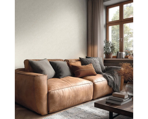 Hellbraunes Ledersofa in einem hellen Wohnzimmer mit Fenster und dezent strukturierter, heller Wandgestaltung.
