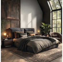 Modernes Schlafzimmer mit gepolstertem Bett, dunkler Holzwandverkleidung, Fenster, Ledersessel und Zimmerpflanze auf Fischgrätparkett.