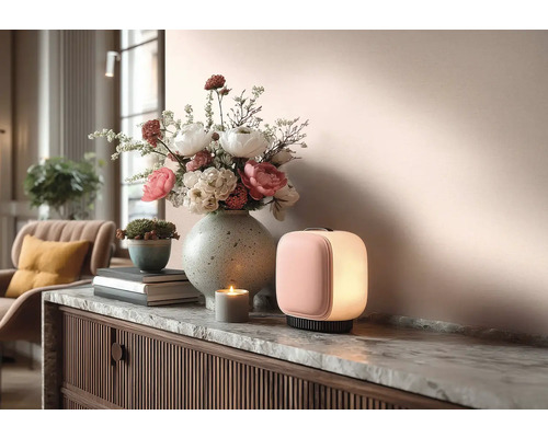 Dekoratives Interieur mit Tischleuchte, Blumenarrangement, Kerze und Kommode