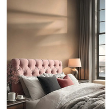 Ein Schlafzimmer mit einem Bett, einem gepolsterten Kopfteil, Kissen, einer Lampe und Vorhängen.