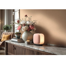 Dekoratives Interieur mit Tischleuchte, Blumenarrangement und Kerze auf einer Kommode.