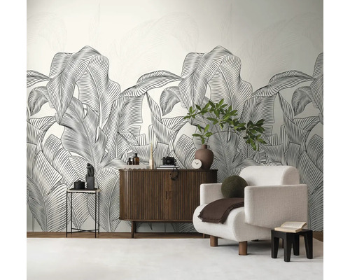 Wohnzimmer mit großformatiger Blättertapete, Sessel und Holzkommode