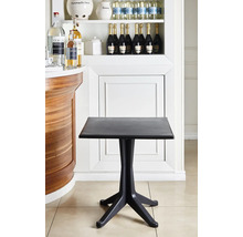 Schwarzer quadratischer Bistrotisch aus Kunststoff mit einem Vierfußgestell in einem hellen, organisierten Innenraum neben einer hölzernen Theke.