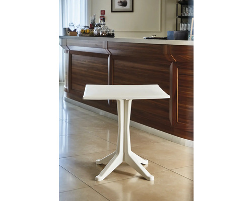 Kleiner Bistrotisch aus Kunststoff vor einer Holztheke in einem hellen, gefliesten Raum.