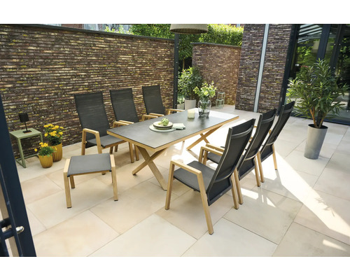 Moderne Garten-Sitzgruppe auf einer hellen Terrasse bestehend aus einem Esstisch mit Holzgestell, sechs Hochlehner-Stühlen und einem Fußhocker.