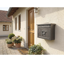 Grauer Briefkasten mit Hornmotiv an einer Hauswand neben einer Haustür.
