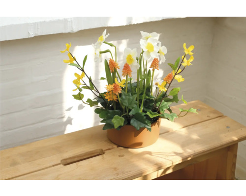 Dekorative Blumengesteck mit Narzissen in Keramiktopf auf Holztisch