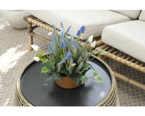 Dekorative Kunstblumen in einem Topf auf einem Rattantisch