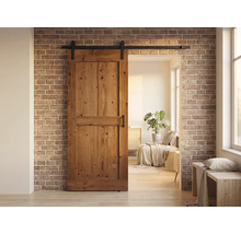 Holzschiebetür vor einer Ziegelwand mit einem Wohnbereich im Hintergrund.