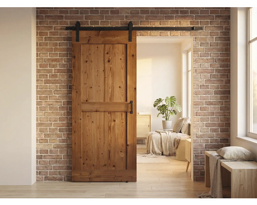 Holzschiebetür vor einer Ziegelwand mit einem Wohnbereich im Hintergrund.