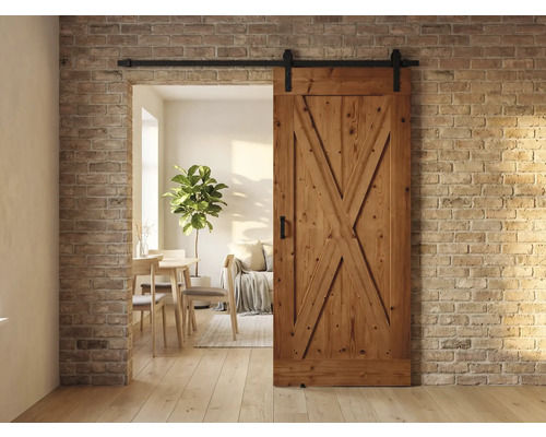 Holzschiebetür im Landhausstil vor einer Backsteinwand