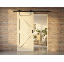 Holzschiebetür im Landhausstil mit Beschlägen vor einer Backsteinwand