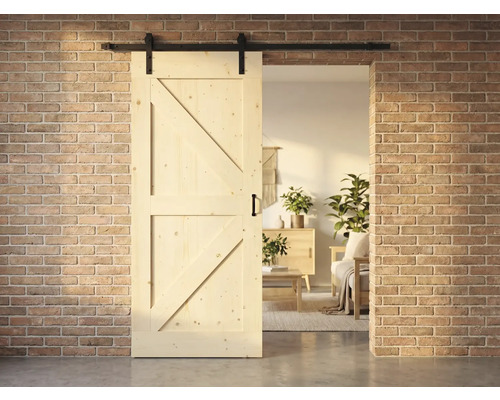 Holzschiebetür im Landhausstil mit Beschlägen vor einer Backsteinwand