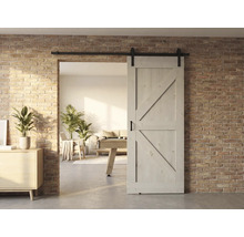 Holzschiebetür vor einer Ziegelwand mit Blick in ein helles Wohnzimmer