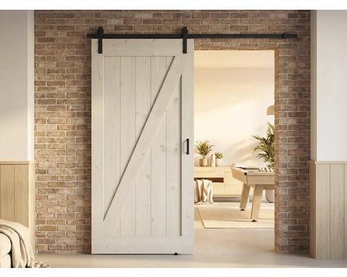 Holzschiebetür im Landhausstil mit Beschlägen vor einer Ziegelwand