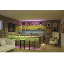 Modern gestaltete Hausbar mit Holzpaneelen, beleuchteter Theke, Barhockern, einem Sofa und einem Sessel in einem gemütlich eingerichteten Raum.