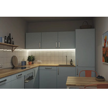 Moderne Einbauküche in L-Form mit hellblauen Fronten, Arbeitsplatte aus Holz und weißem Fliesenspiegel. Inklusive Backofen und Spüle.