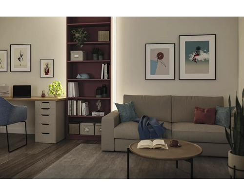 Modernes Wohnzimmer und Heimbüro mit beigem Sofa, rundem Couchtisch, lila Bücherregal, Schreibtisch und blauem Stuhl an hellen Wänden.