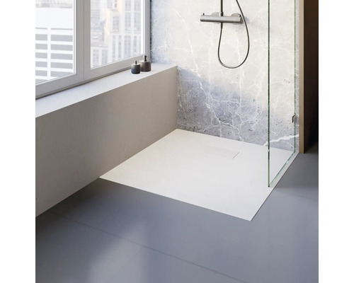 Ebenerdige Dusche mit Glasabtrennung und Duscharmatur vor einer Marmorwand