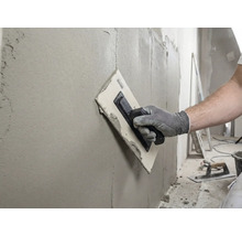 Handwerker glättet Wand mit einer Glättkelle und Spachtelmasse.