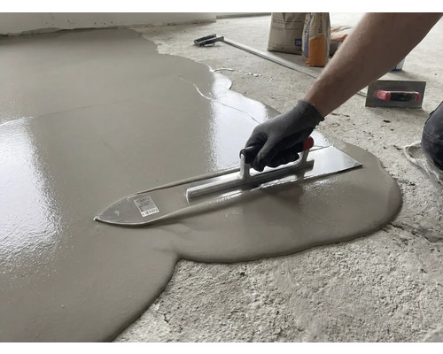 Verarbeiten von Ausgleichsmasse mit einer Glättkelle auf einem Boden