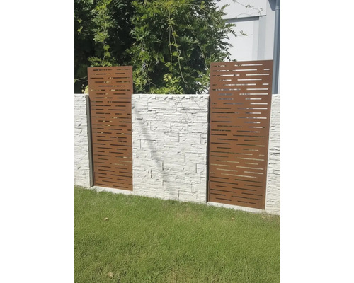 Dekorative Sichtschutzelemente aus Metall mit horizontalen Ausschnitten vor einer Steinmauer