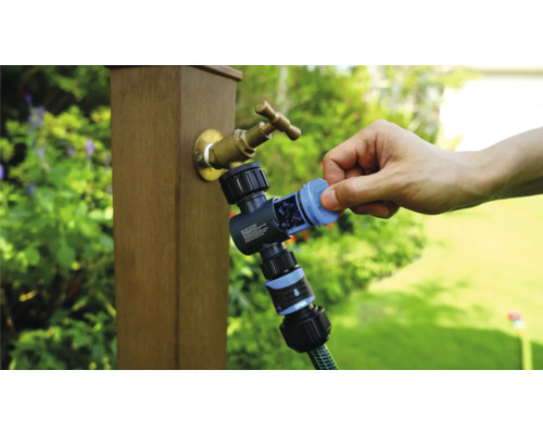 Gartenwasserhahn mit Wasserverteiler und angeschlossenem Gartenschlauch in der Anwendung.