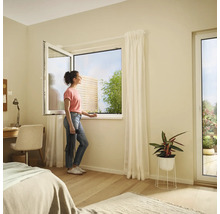 Helles Schlafzimmer mit Kippfenster und einer Frau, die nach draußen schaut