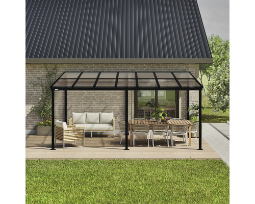 Freistehende Terrassenüberdachung mit Möbeln auf einer Holzterrasse vor einem Haus.